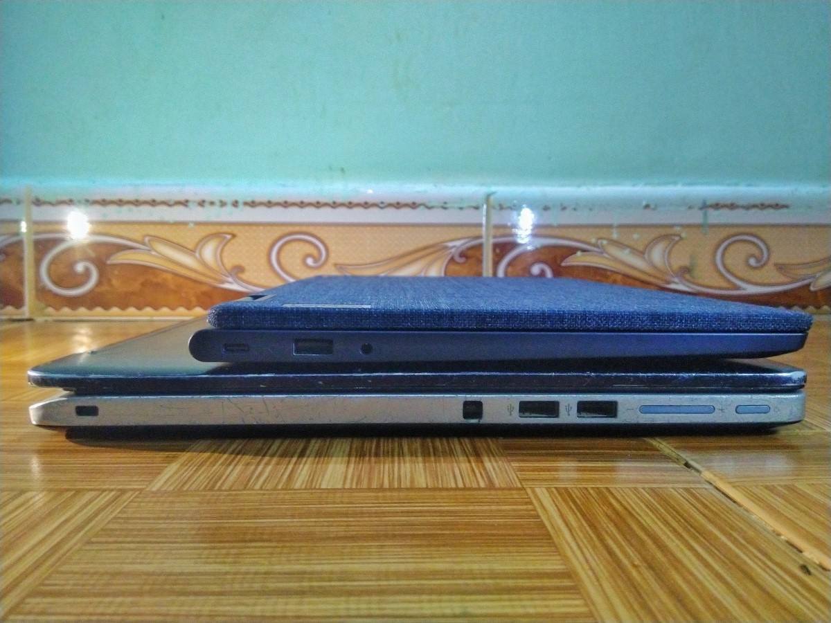 Ảnh máy Lenovo Yoga 6 đặt trên chiếc ASUS TP500LA, nhìn từ phía cạnh trái. Cả hai chiếc laptop đang được gấp lại.